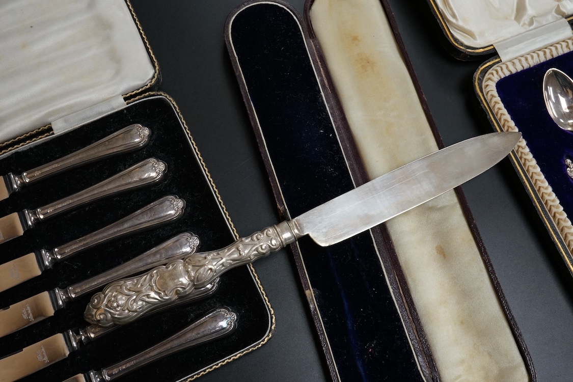 A cased set of twelve Edwardian silver apostle teaspoons with a pair of sugar tongs, Cooper Brothers & Sons, Sheffield, together with a cased Victorian silver bread knife and a cased set of six silver handled steel tea k
